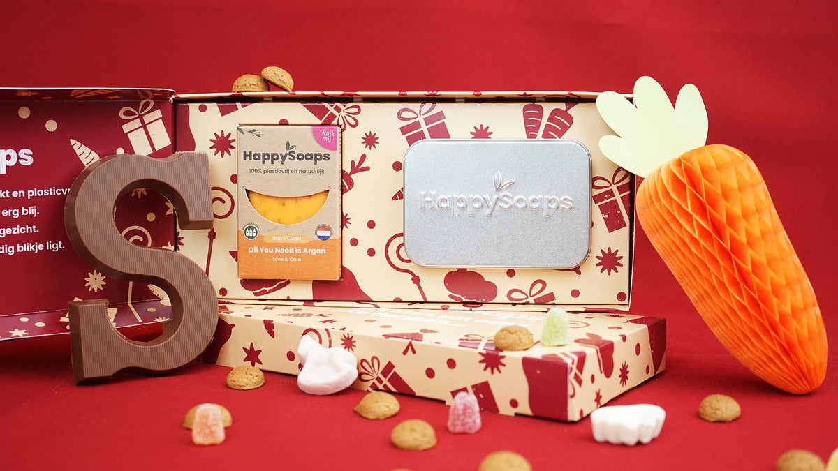Geopende Sinterklaas Giftbox met de Body Wash Bar en het reisblikje, op rood met een chocoladeletter en pepernoten