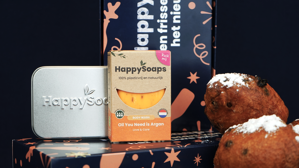 Close-up van het reisblikje en de Body Wash Bar Oil You Need is Argan op de Nieuwjaarscadeau Giftbox, met oliebollen