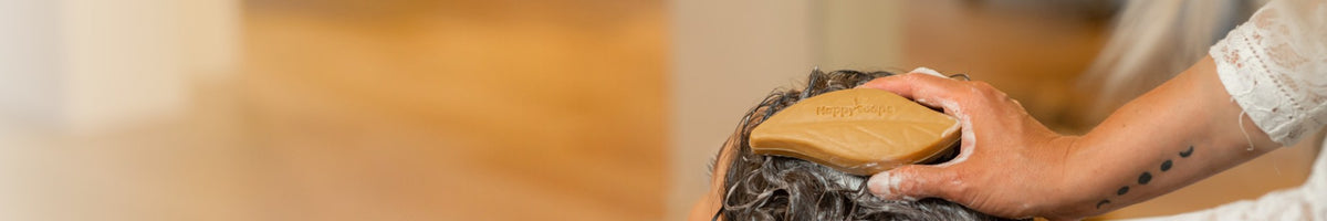 Shampoo bar wordt door nat haar gemasseerd bij de wasbak in een salon